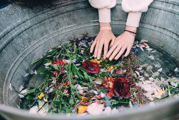 flower bath with hands in the water and herbs and flowers